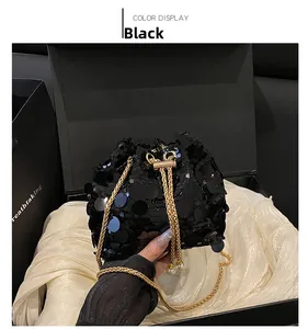 Detail of black sequined bucket bag with golden chain strap and drawstring closure