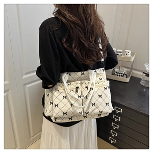 Detail of cream quilted tote bag with black bow print and multiple functional zipper pockets