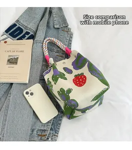 Top view of knit bucket bag with strawberry pattern and phone for size comparison