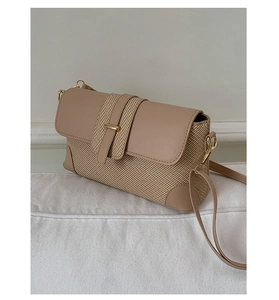 Detail of beige woven straw and leather shoulder bag with golden metal buckle clasp