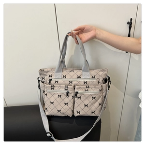 Detail of corduroy tote bag featuring black bow patterns and three front zipper pockets
