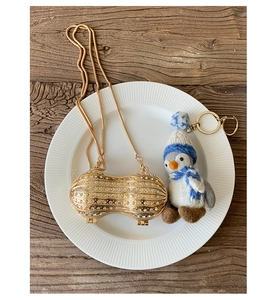 Macro detail of peanut shaped evening bag with white rhinestones and a penguin charm