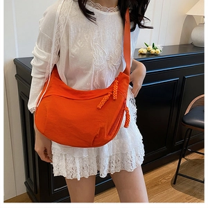 Détail du sac bandoulière orange en forme de croissant avec tirette de fermeture tressée