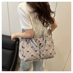 Detail of canvas tote bag with black bow print and multiple front zipper pockets