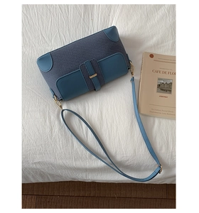 Detailed top view of a textured fabric and faux leather shoulder bag on a soft white surface