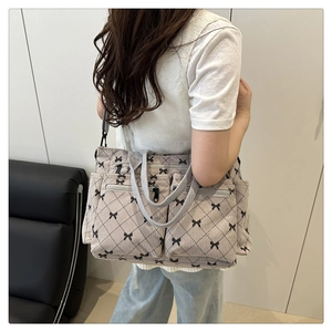 Detail of beige corduroy tote bag with bow prints and practical side pockets shown on model