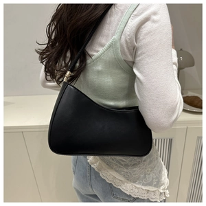 Side view of a black leather hobo bag worn by a model with golden buckle detail