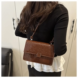 Detailed back view of a brown crocodile pattern crossbody bag on model with metal buckle