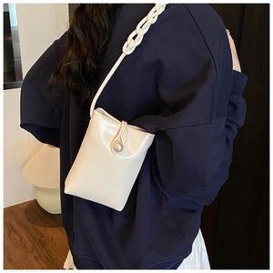 Détail d'un mini sac de téléphone crème avec fermoir perle et bandoulière torsadée