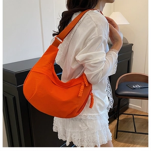 Détail du sac hobo en nylon orange vif avec sangle réglable et tirette de zip tressée