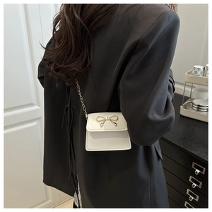 Detailed back view of a white mini square bag with golden bow clasp and chain strap