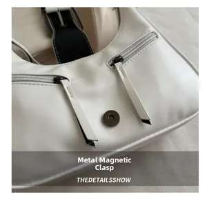 Dettaglio della borsa bianca con fibbia magnetica in metallo e tasche con cerniera