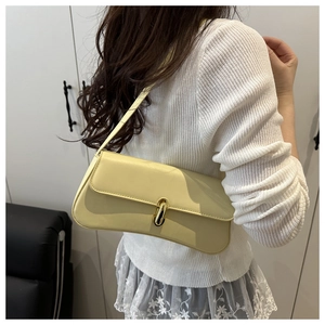 Detail of creamy yellow shoulder bag with golden twist lock on textured knit outfit
