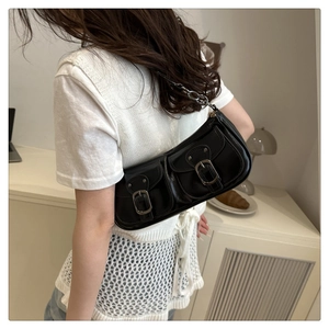 Detailed view of black retro baguette bag featuring front pockets and silver buckles