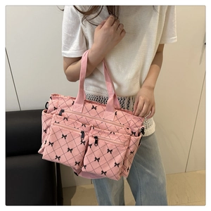 Detailed view of pink quilted tote bag with black bows and multiple functional zipper pockets