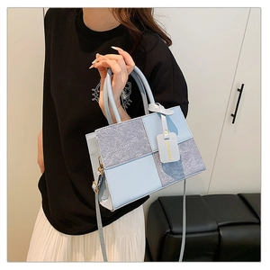 Detail of light blue leather patchwork handbag with silver glitter panels and top handles