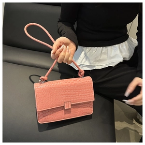 Macro detail of pink crocodile texture and magnetic flap closure on a luxury handbag