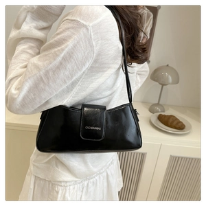 Detail of elegant black patent leather shoulder bag with a silver brand logo on the flap