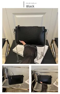 Détail du sac noir à texture crocodile avec chaîne argentée et rivets métalliques