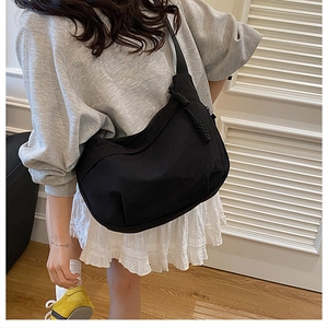 Détail du sac demi-lune en nylon noir avec une tirette de fermeture à nœud tressé