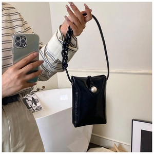 Close-up of a glossy black phone bag featuring a large pearl clasp and acrylic chain strap