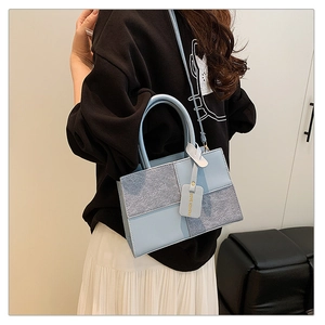 Model wearing a light blue patchwork crossbody bag with grey felt texture and stylish tag
