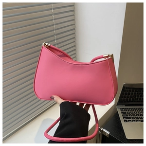 Detail of pink matte leather shoulder bag with gold hardware held in hand