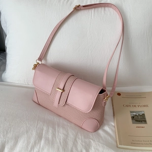 Pink vintage shoulder bag with textured patchwork design and gold buckle on a soft background