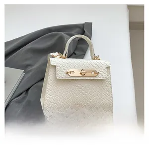 Detail of white crocodile texture handbag featuring a golden clasp and elegant top handle