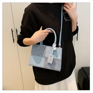 Detail of trendy patchwork handbag showing blue leather and grey brushed fabric textures