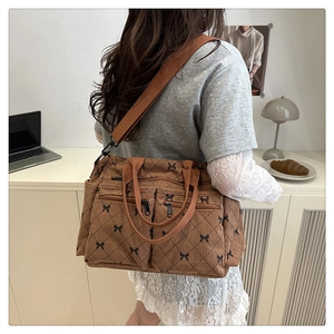 Detailed view of brown corduroy tote bag with black bow grid pattern and wide shoulder strap