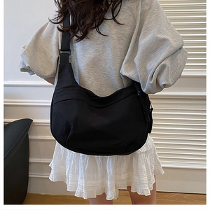 Détail d'un sac demi-lune noir en nylon montrant la bandoulière réglable et le zip tressé