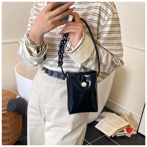 Detail of black faux leather mini bag with large pearl clasp and thick chain strap