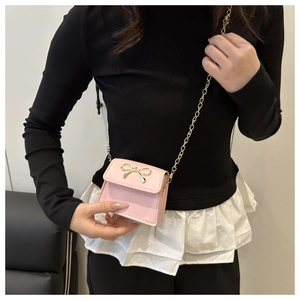 Detail of light pink mini crossbody bag with golden bow buckle and chain strap