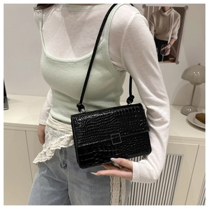 Detail of black crocodile texture handbag with minimalist silver square metal clasp buckle
