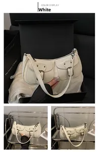 Close-up of white glossy leather shoulder bag featuring dual pockets and metal buckles