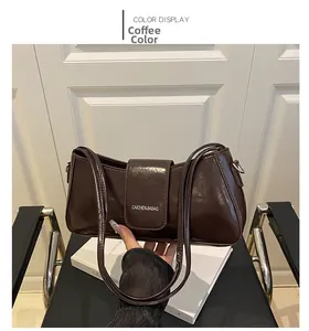 Detailed view of the coffee brown glossy patent leather texture and silver logo on the bag