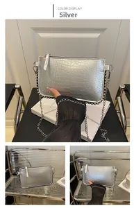 Détail du sac argenté texture crocodile avec bordure perlée noire et chaîne