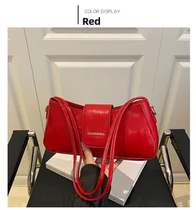 Close-up of red glossy leather shoulder bag with white printed brand logo