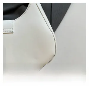 Close-up of fine stitching and smooth white leather texture on a minimalist saddle bag