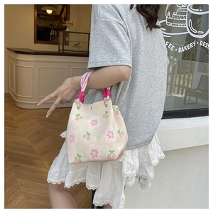 Detail der gestrickten Beuteltasche mit Blumen-Kirsch-Muster und rosa Griffen
