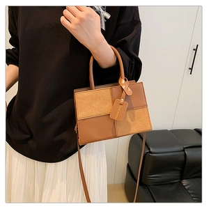Detail of brown patchwork handbag featuring smooth leather and suede textures with a tag