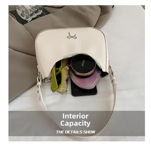 Internal capacity of beige crescent shoulder bag with metal bow detail and essentials