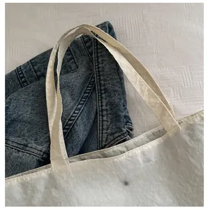 Detail showing the white pleated texture tote bag with a metallic fashion logo buckle