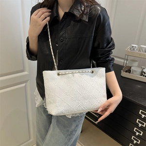 Elegant white tweed tote bag with gold chain strap shown on model in black leather jacket