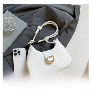 Size comparison of white crescent shoulder bag next to a smartphone with D-ring detail