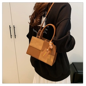 Detailed macro view of a brown patchwork handbag with a fashion tag and adjustable strap