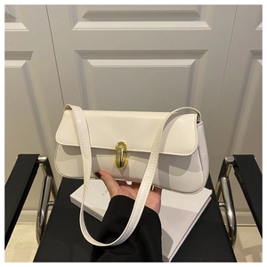 Detailed shot of cream white leather shoulder bag with elegant gold metal clasp detail