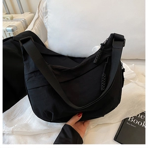 Détail du sac dumpling en nylon noir avec bandoulière large et tirette tissée