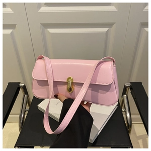 Detail of pink faux leather underarm bag with gold buckle held over a book